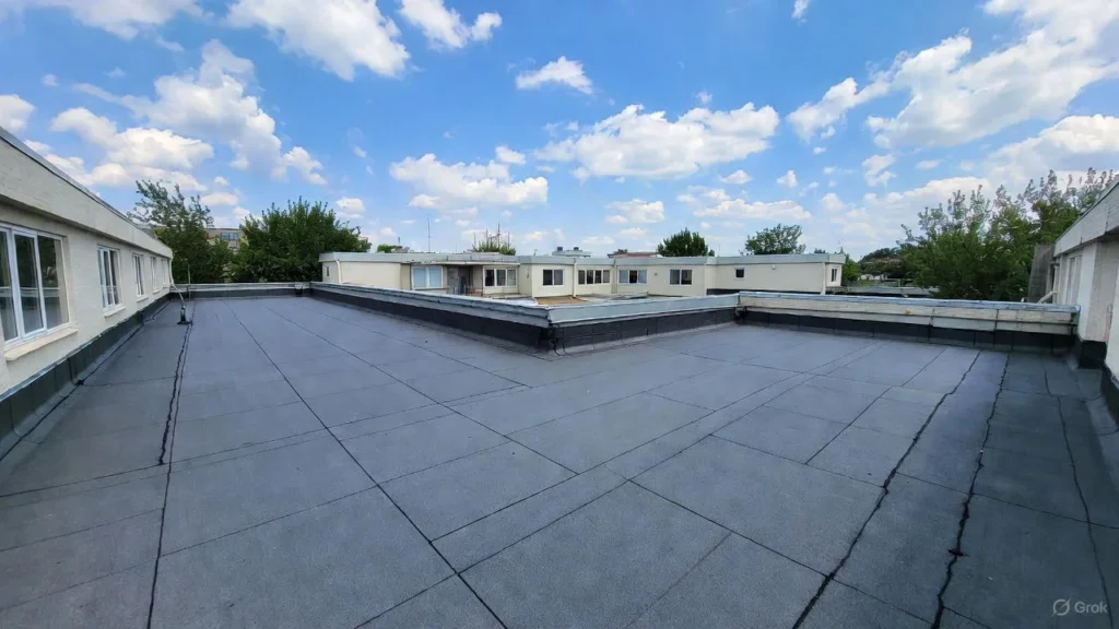 A large area of commercial rubber roofing (black EPDM membrane) installed on a low-slope building, showing professional sealing around vents and parapet edges.