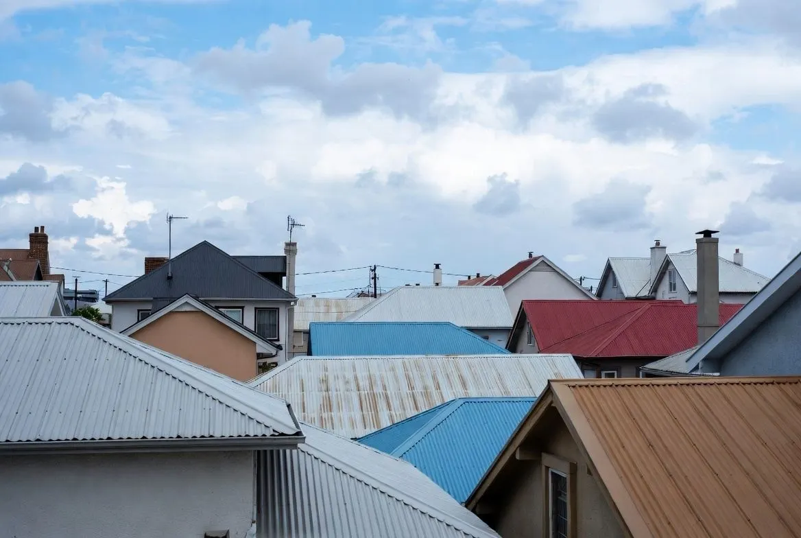 A collection of standing seam metal roof colors and textures, featuring samples in charcoal, bronze, forest green, and slate grey to showcase available design options